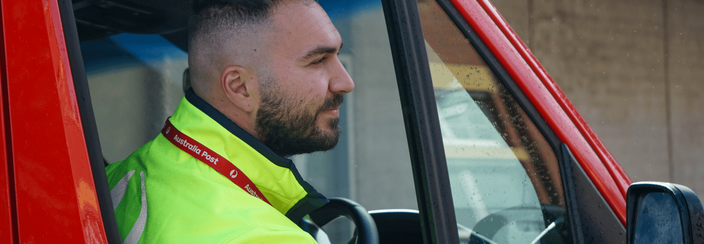 Van driver sitting in a red van leans out of driver’s side window looking at the road ahead.