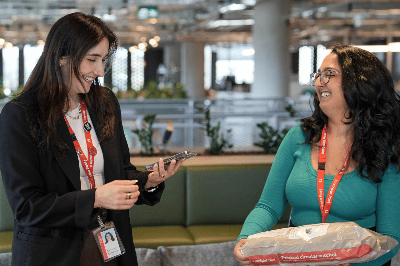 Two team members laughing together in office while holding a circular satchel