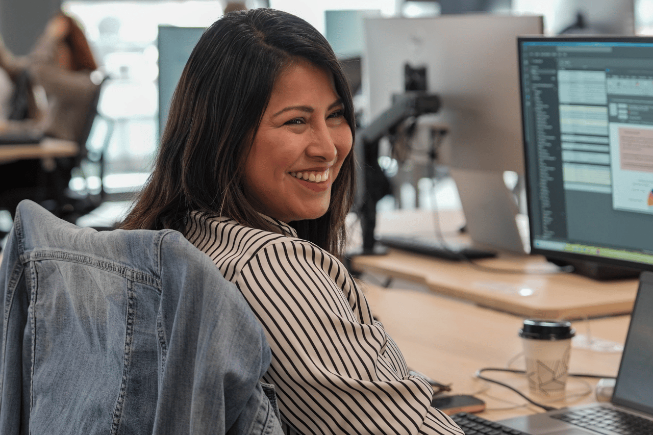 Team member at desk smiling at the person sitting next to her