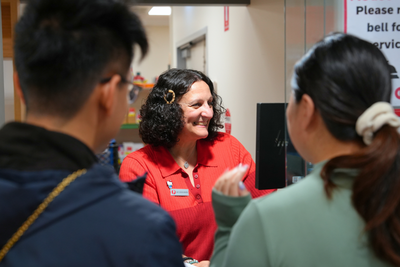 Retail team member serving two customers at counter and smiling at screen