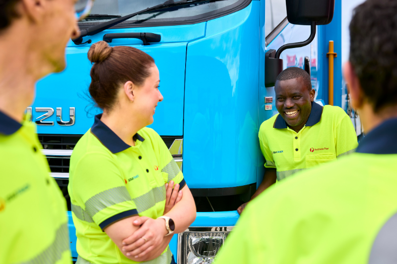 A group of transport team members standing outside chatting together next to a blue StarTrack truck