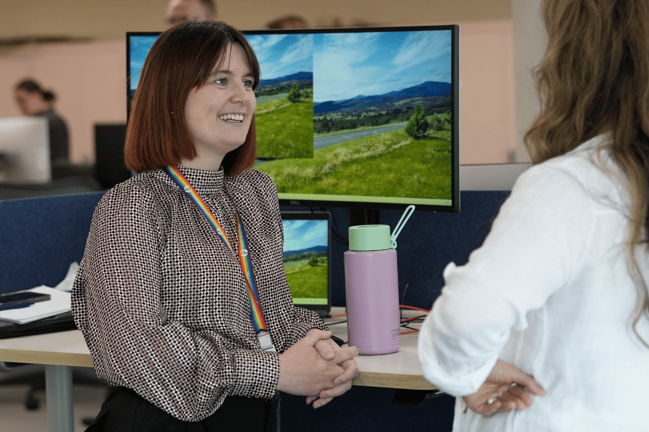 Office team member talking to a colleague at a standing desk