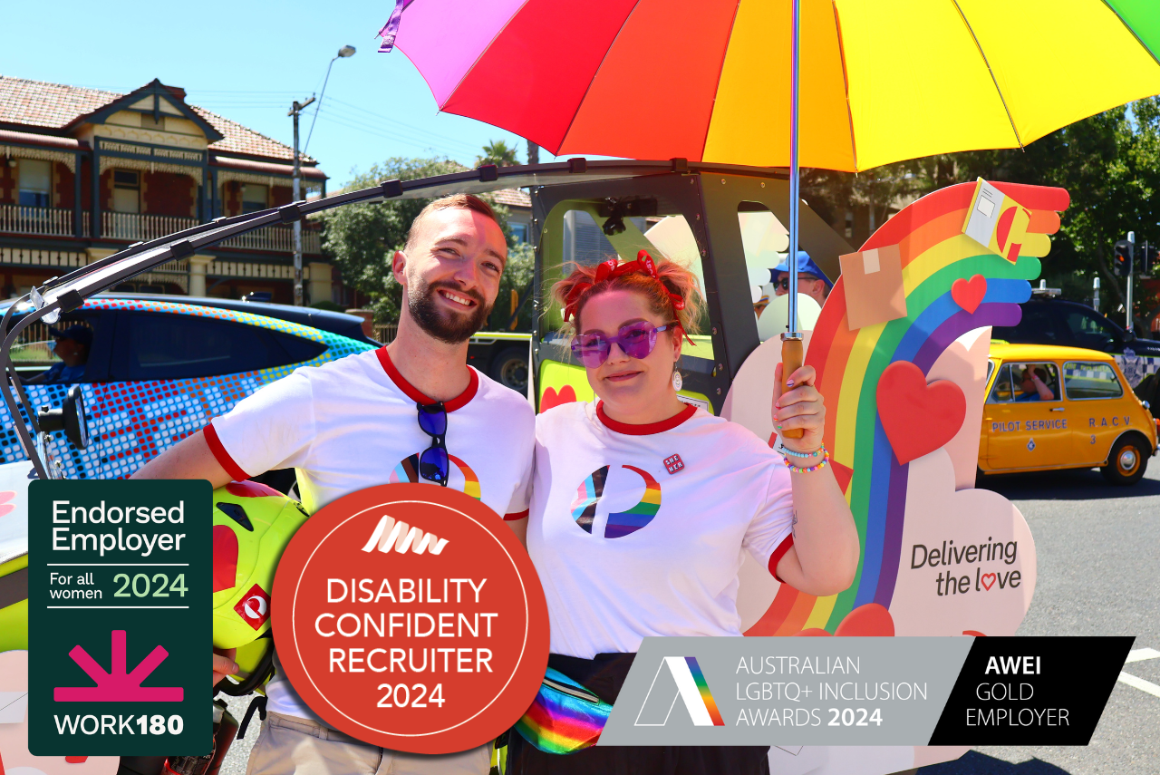 An office team member in a wheelchair smiles to the side. Overlayed images read ‘Disability confident recruiter 2023’ and ‘Australian LGBTQ Inclusion Awards 2023-2026’.